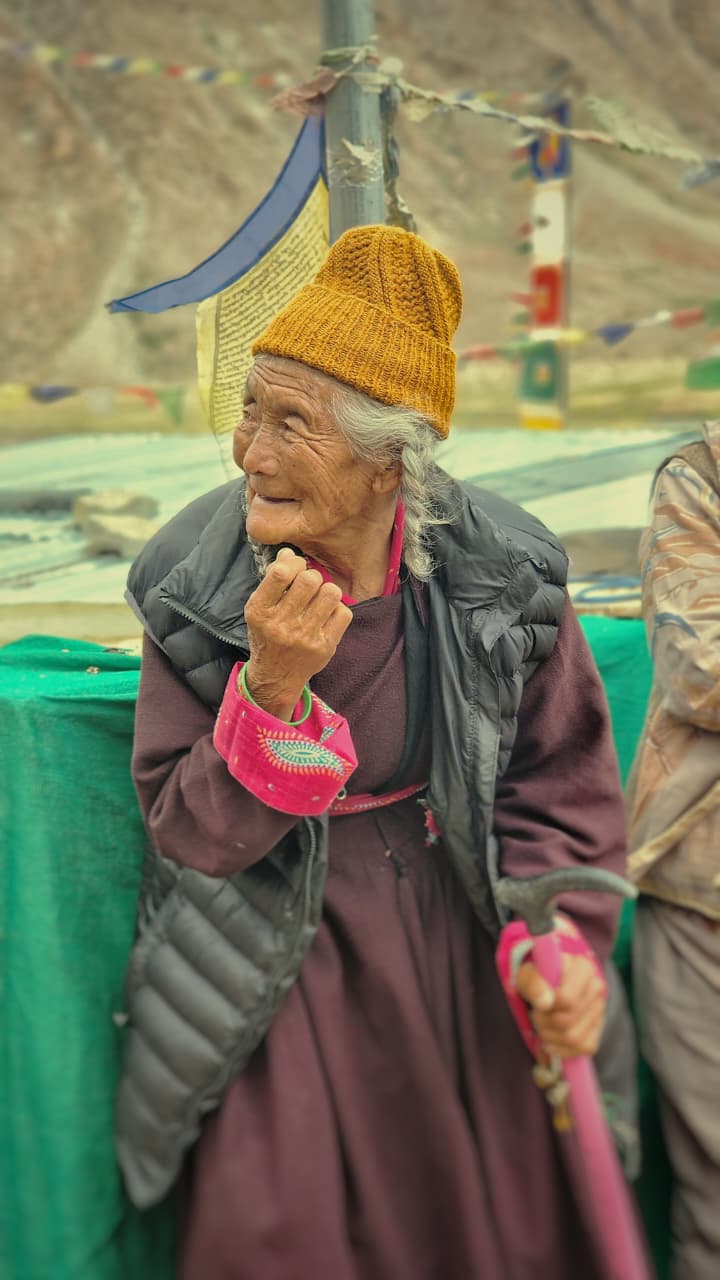 A Ladakhi elder beside fluttering prayer flags
